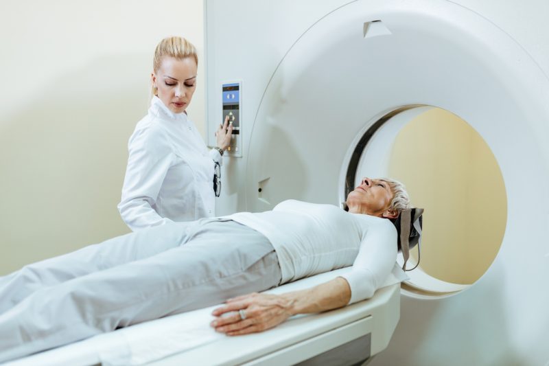 Radiologist supervising CT scan procedure of her mature patient.